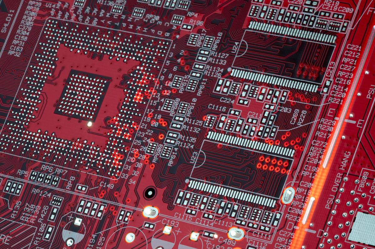 Detailed shot of a red motherboard showcasing electronic components and circuits.