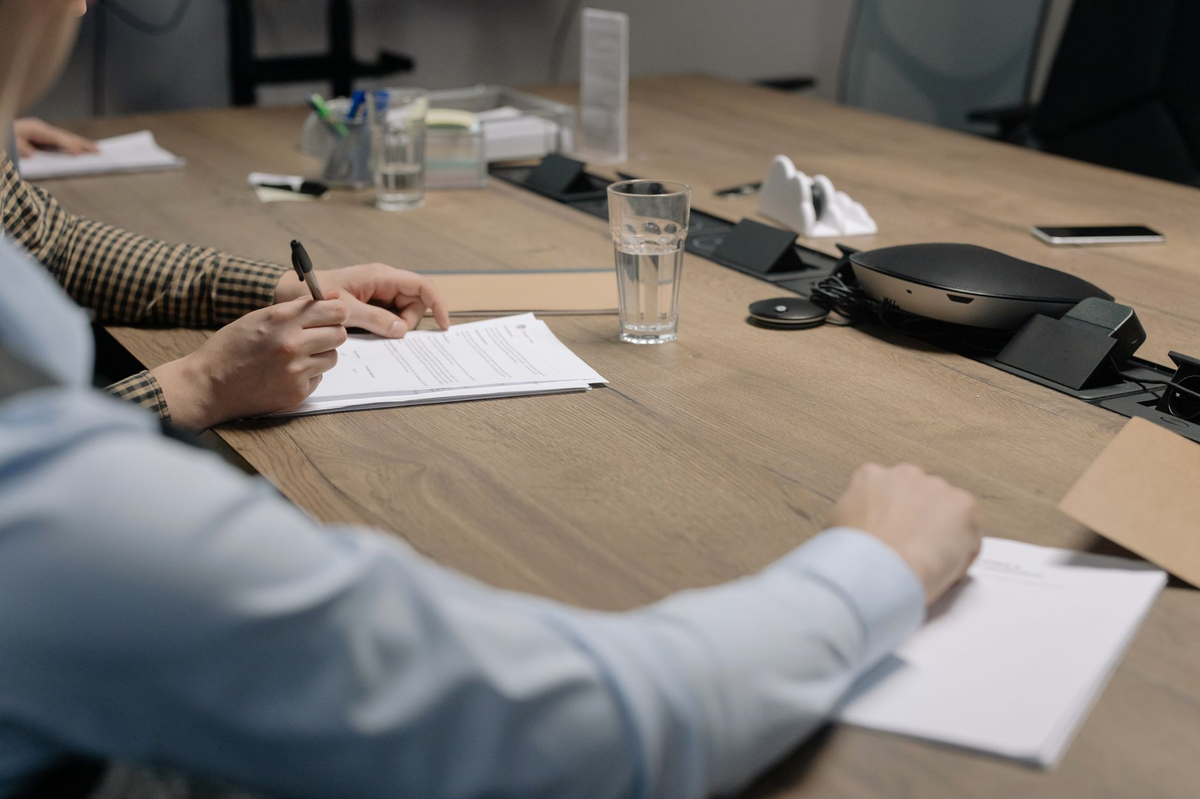 Professional setting of a business meeting with individuals signing documents on a conference table.