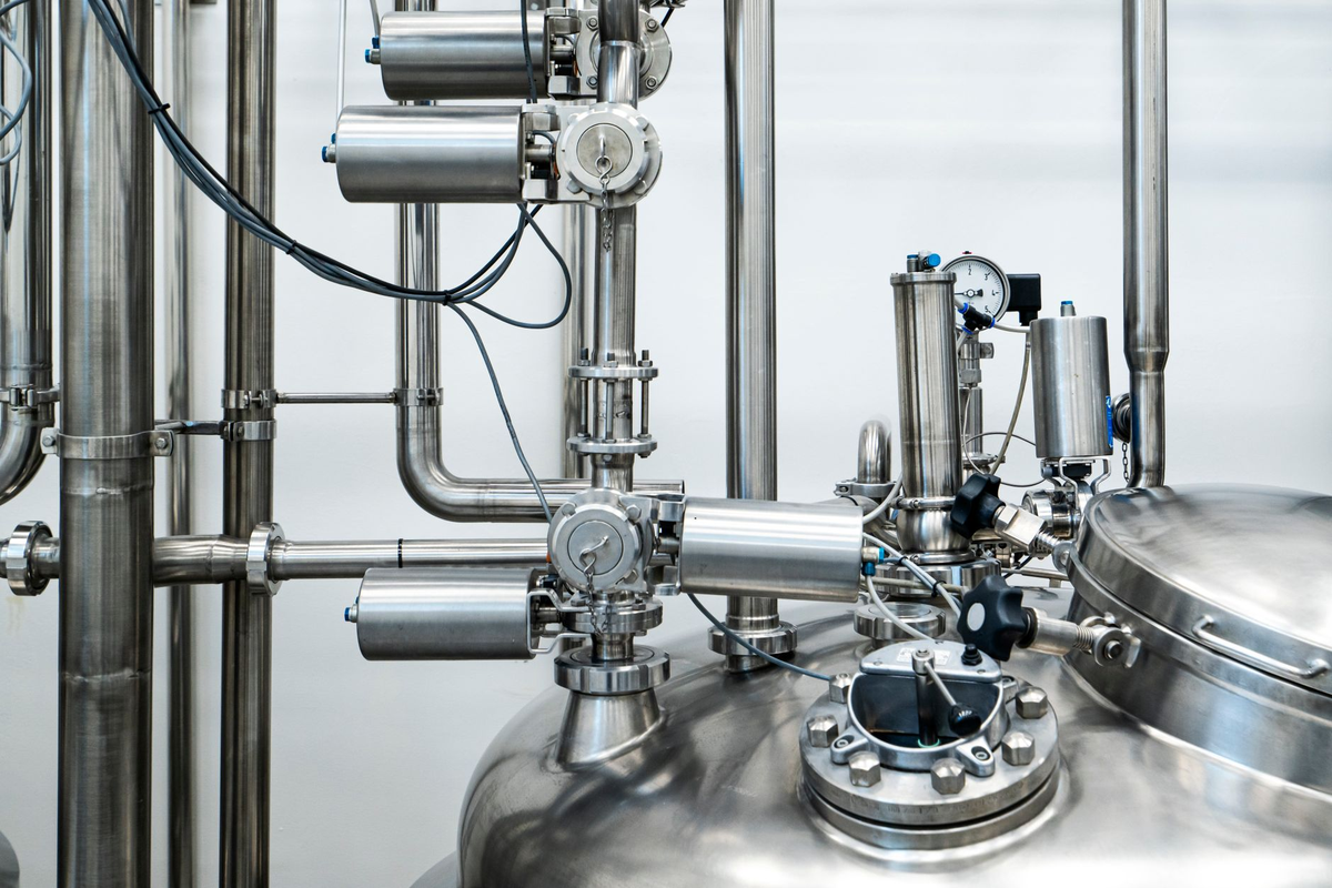 Close-up of stainless steel machinery and pipes in an industrial setting, showcasing modern engineering.